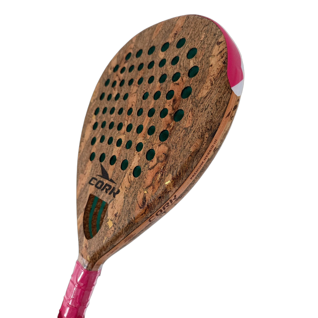 A close-up of a cork paddle racket head with a natural cork texture, green sound holes, a pink and white wrapped handle, and the brand name CORK visible on the face.